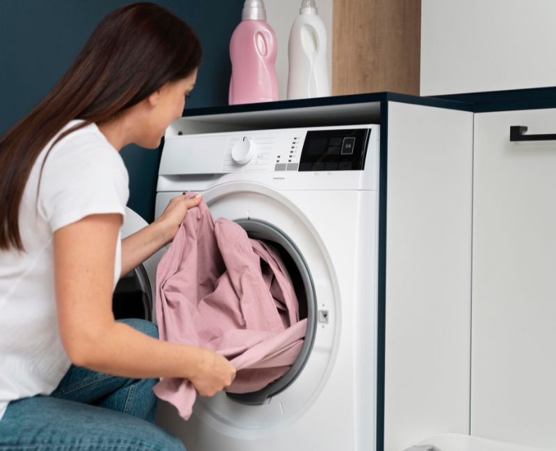 Woman Washing Linen Tablecloth in Washing Machine Woman Washing Linen Tablecloth in Washing Machine