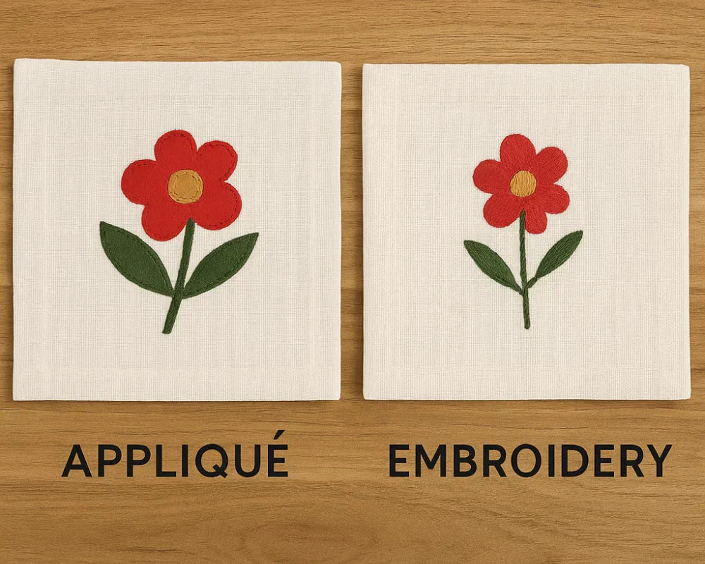 Two linen napkins showing a red flower—one with appliqué, the other with embroidery—on a wooden surface. Two linen napkins showing a red flower—one with appliqué, the other with embroidery—on a wooden surface.