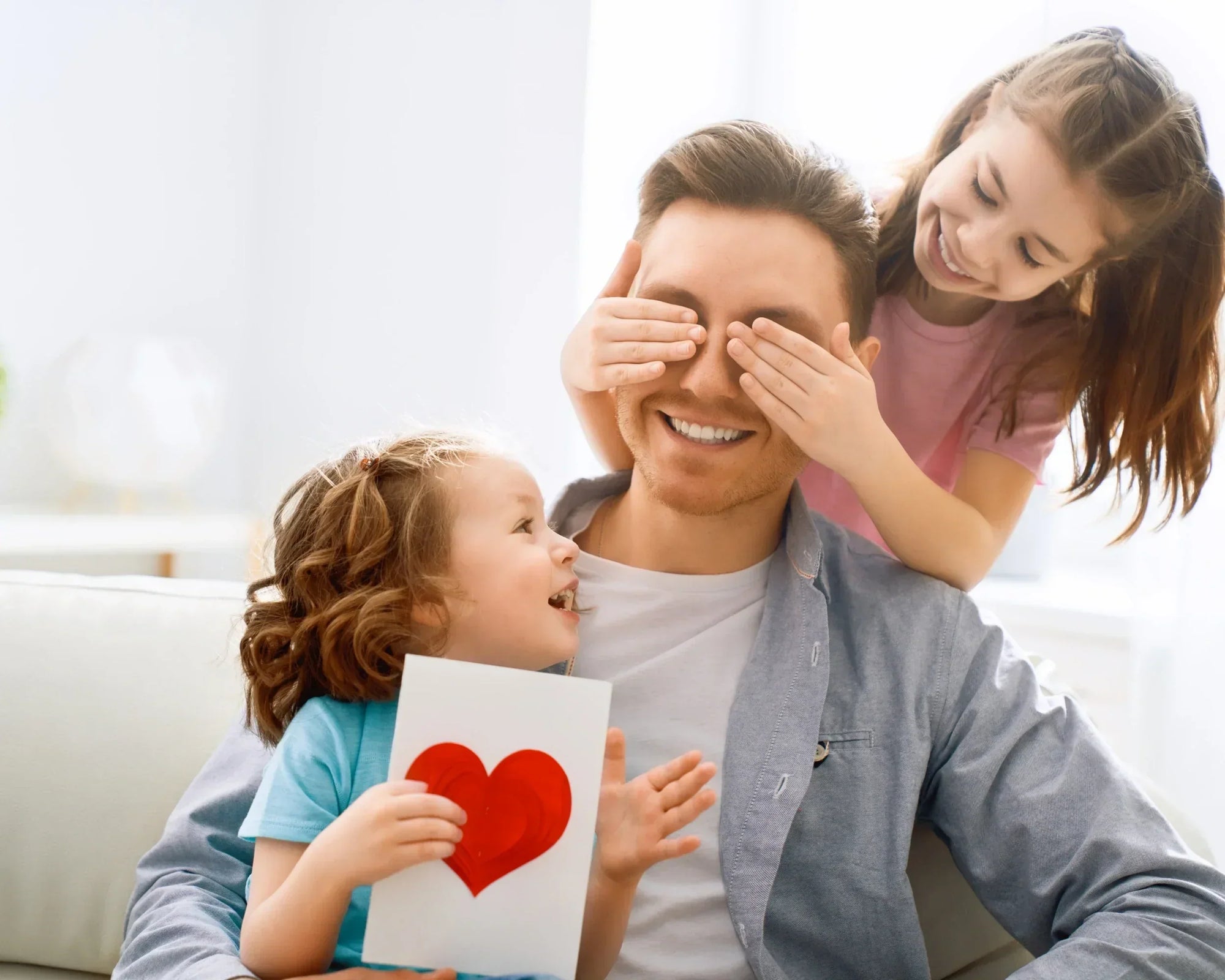 Father smiling while receiving a handmade card from his children, celebrating Father's Day at home. Father smiling while receiving a handmade card from his children, celebrating Father's Day at home.