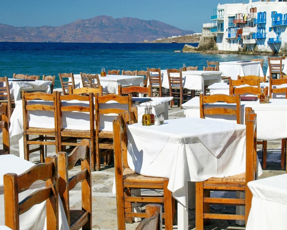 Outdoor dining area with wooden chairs and white tablecloths by the sea. Outdoor dining area with wooden chairs and white tablecloths by the sea.