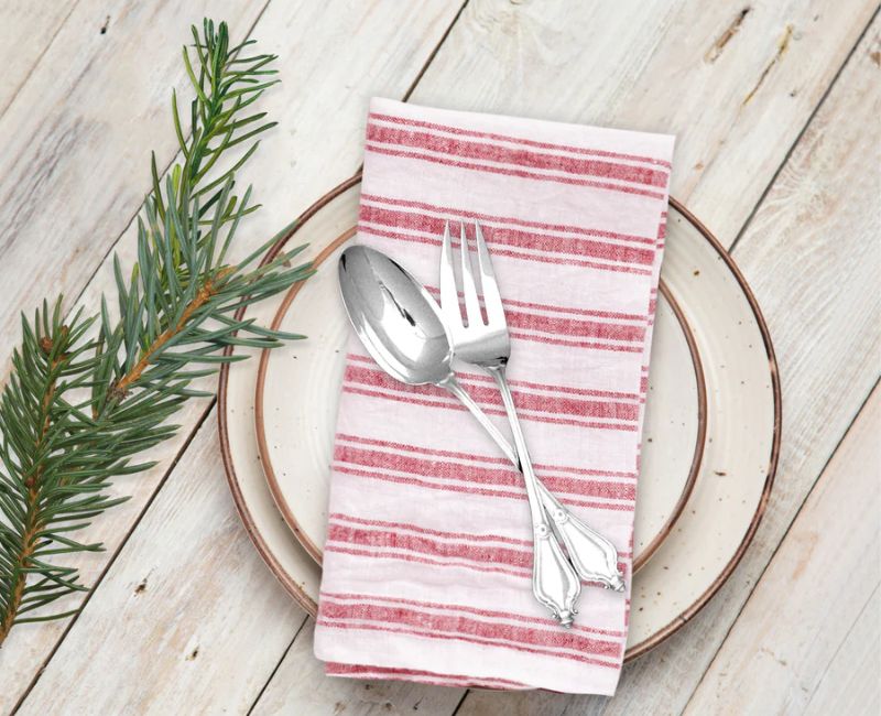 Beige linen napkins folded neatly on a wooden table, with elegant tableware and a cozy country-style dining ambiance Beige linen napkins folded neatly on a wooden table, with elegant tableware and a cozy country-style dining ambiance