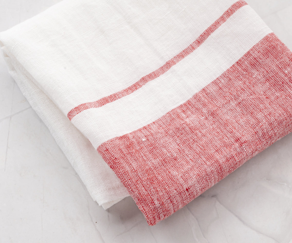 A red and white striped Belgian linen tea towel laid out on a surface. A red and white striped Belgian linen tea towel laid out on a surface.