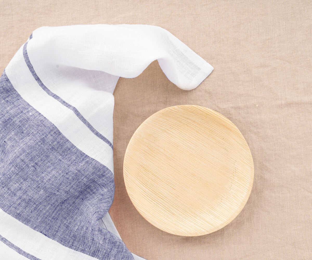 Wooden plate with a Belgian-striped towel on beige linen. Wooden plate with a Belgian-striped towel on beige linen.