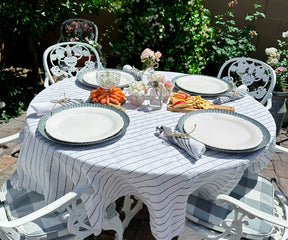 Round linen tablecloth in a rustic dining room with wooden chairs and floral centerpiece.