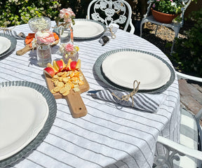 Round linen tablecloth on a patio table, set for an outdoor lunch with colorful dishes.