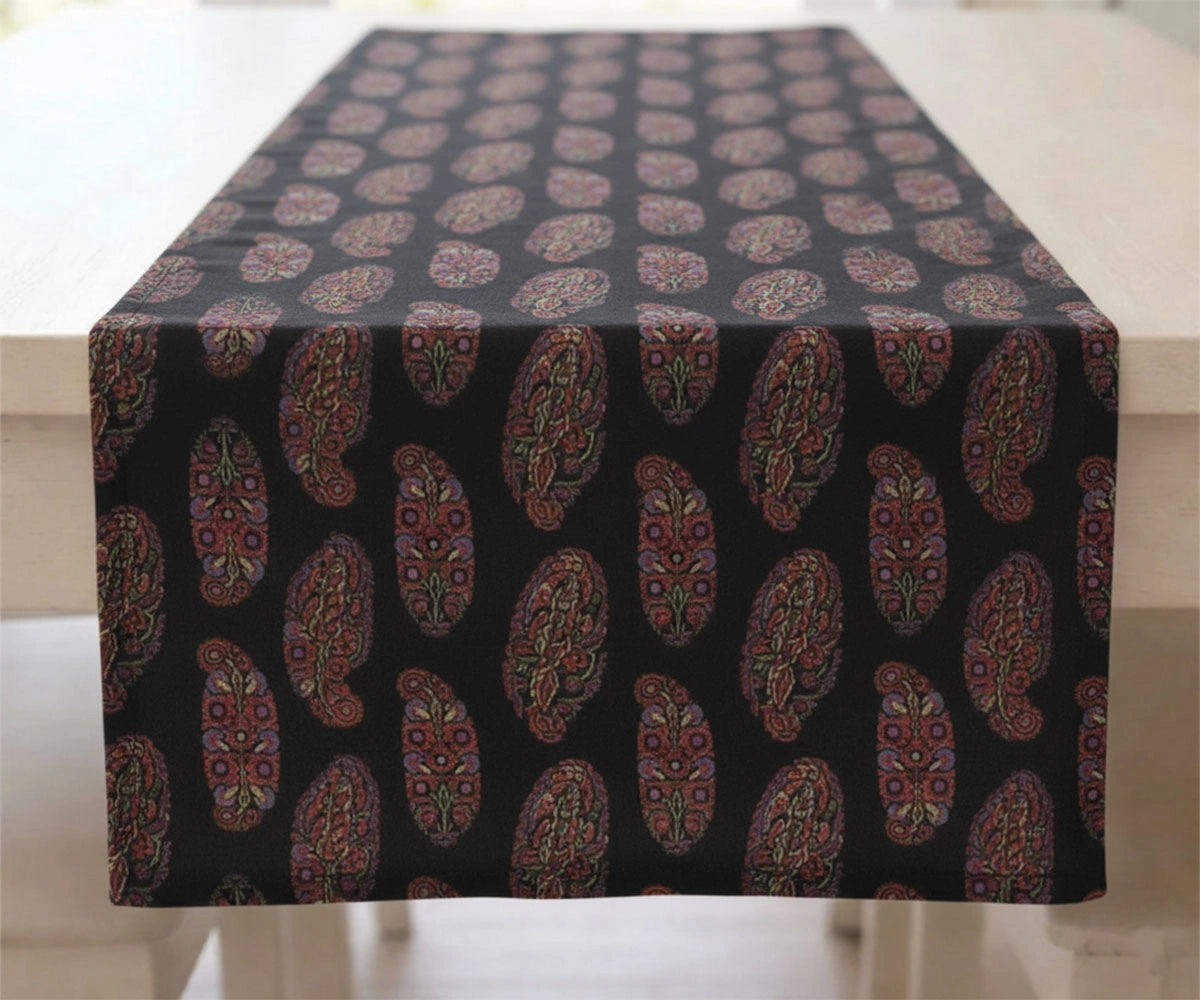 Black tablecloth with red and gold paisley pattern draped over a table Black tablecloth with red and gold paisley pattern draped over a table