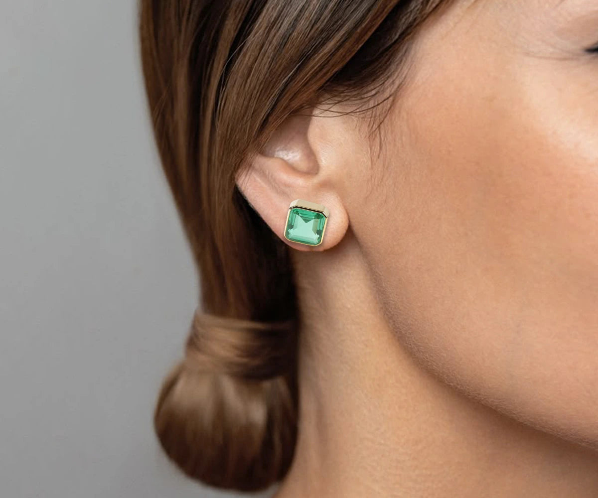 Gold stud earrings with 10mm Asscher-cut emerald green quartz stones, set in 18K gold-plated brass with secure push-back closure. Gold stud earrings with 10mm Asscher-cut emerald green quartz stones, set in 18K gold-plated brass with secure push-back closure.
