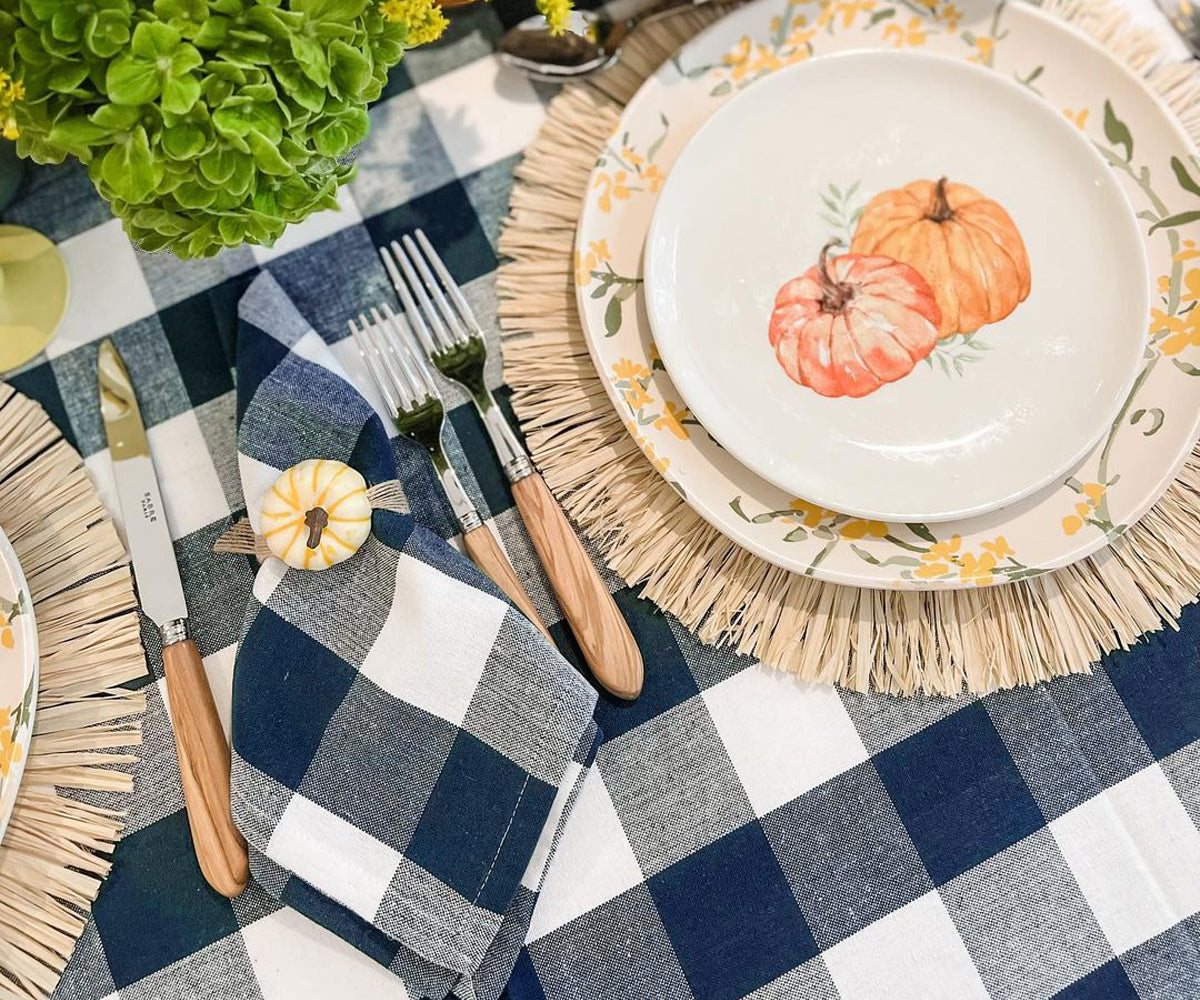 Festive table with pumpkin plate, nay blur checkered tablecloth, and wooden cutlery. Festive table with pumpkin plate, nay blur checkered tablecloth, and wooden cutlery.