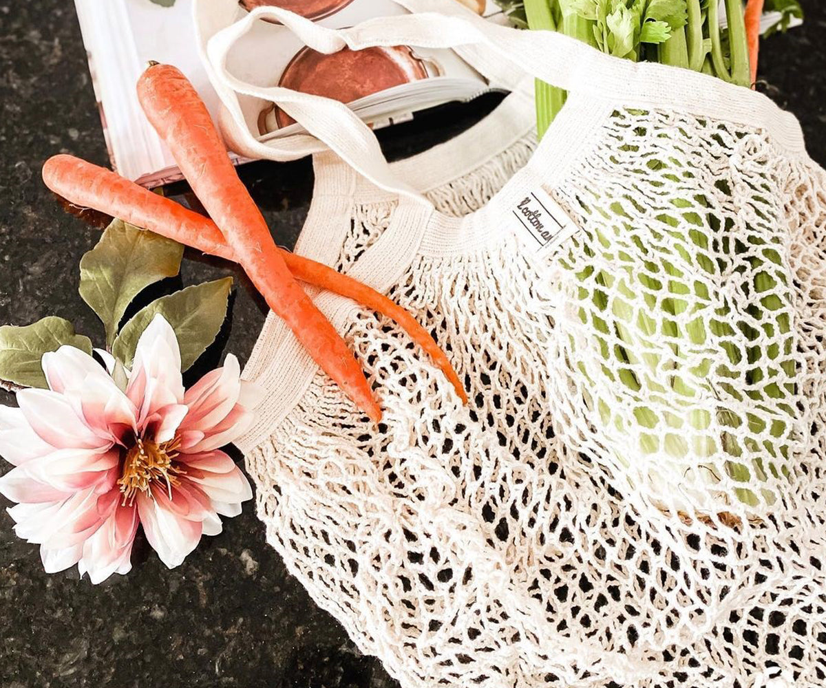 Carrots and mixed vegetables visible in a white cotton mesh bag Carrots and mixed vegetables visible in a white cotton mesh bag