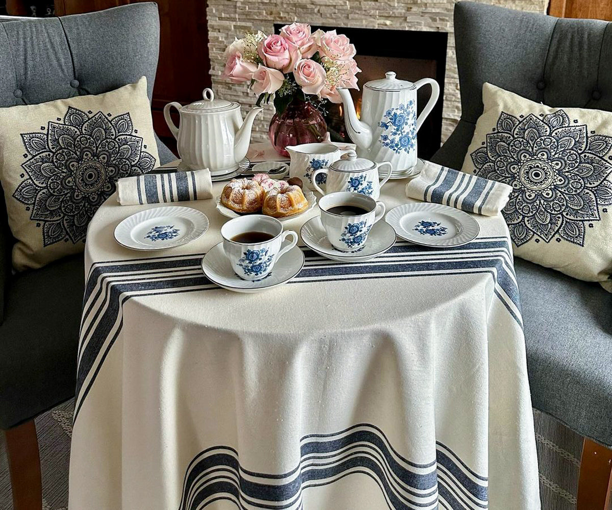 Several 60-inch round tablecloths neatly arranged on a table, showcasing a variety of colors and patterns, ready to add charm and style to any dining setting.