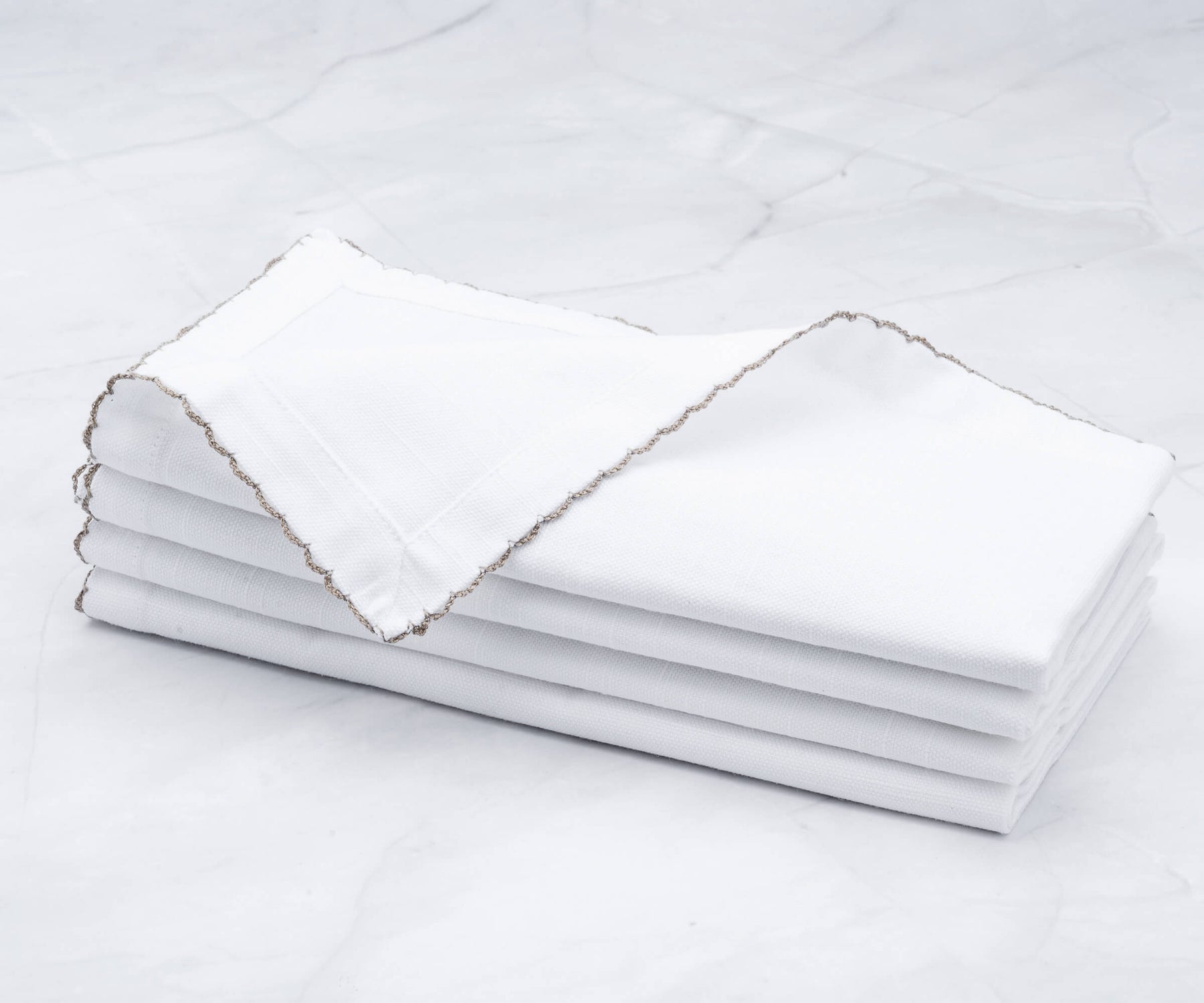 Quartet of shell edge napkins elegantly folded on marble Quartet of shell edge napkins elegantly folded on marble