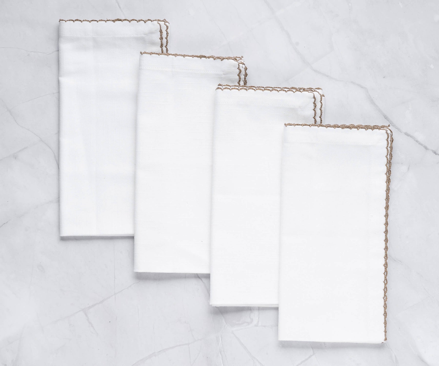 Four luxurious shell edge napkins with gold trim arranged on a marble countertop Four luxurious shell edge napkins with gold trim arranged on a marble countertop