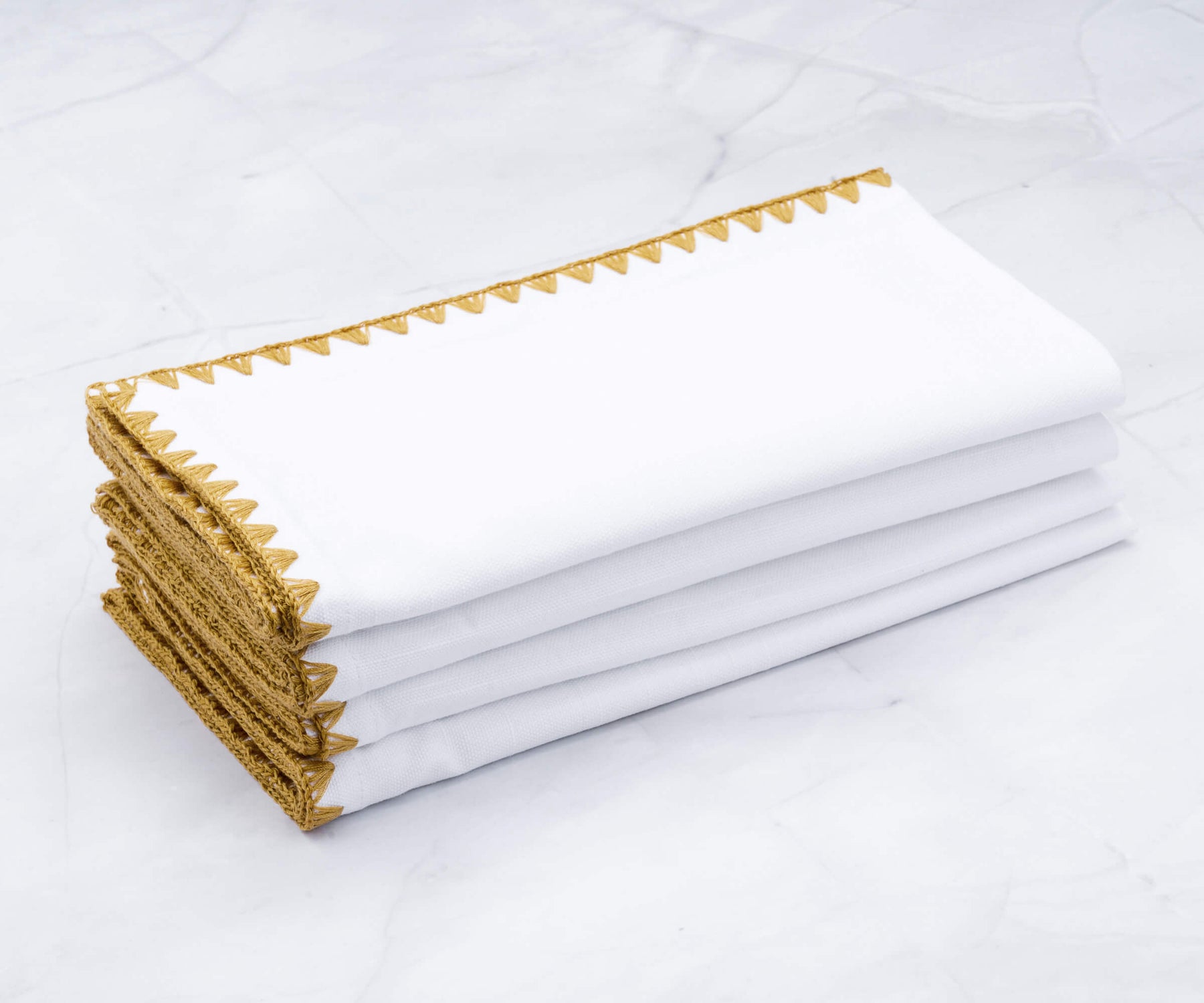 Luxurious white linen napkins with delicate gold shell trim Luxurious white linen napkins with delicate gold shell trim
