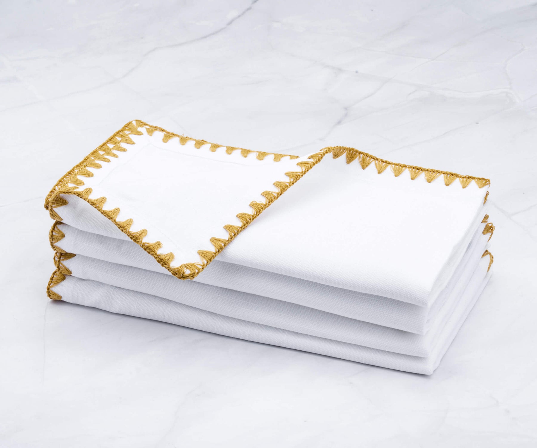 Neat stack of shell edge cloth napkins adorned with gold edges Neat stack of shell edge cloth napkins adorned with gold edges