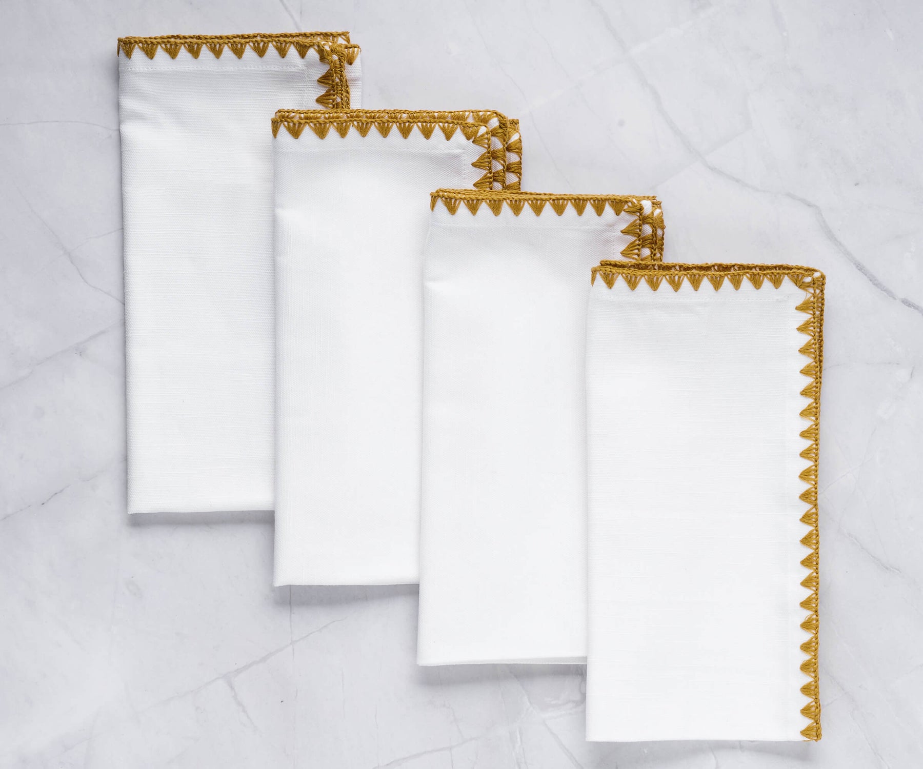 Quartet of white wedding napkins with shell edge and gold detailing Quartet of white wedding napkins with shell edge and gold detailing