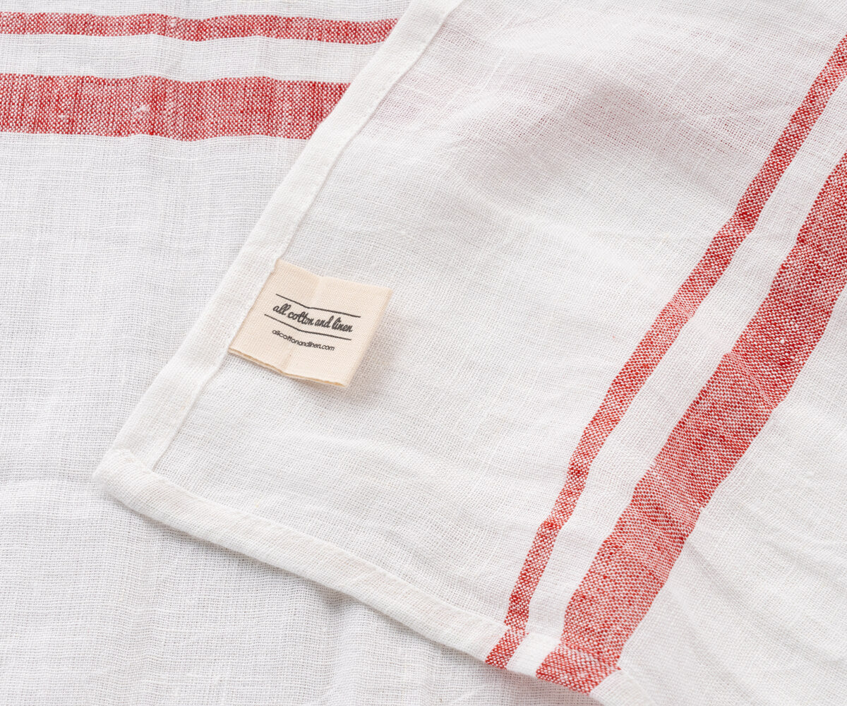 Close-up of a white linen towel with red french style stripes and a fabric tag Close-up of a white linen towel with red french style stripes and a fabric tag