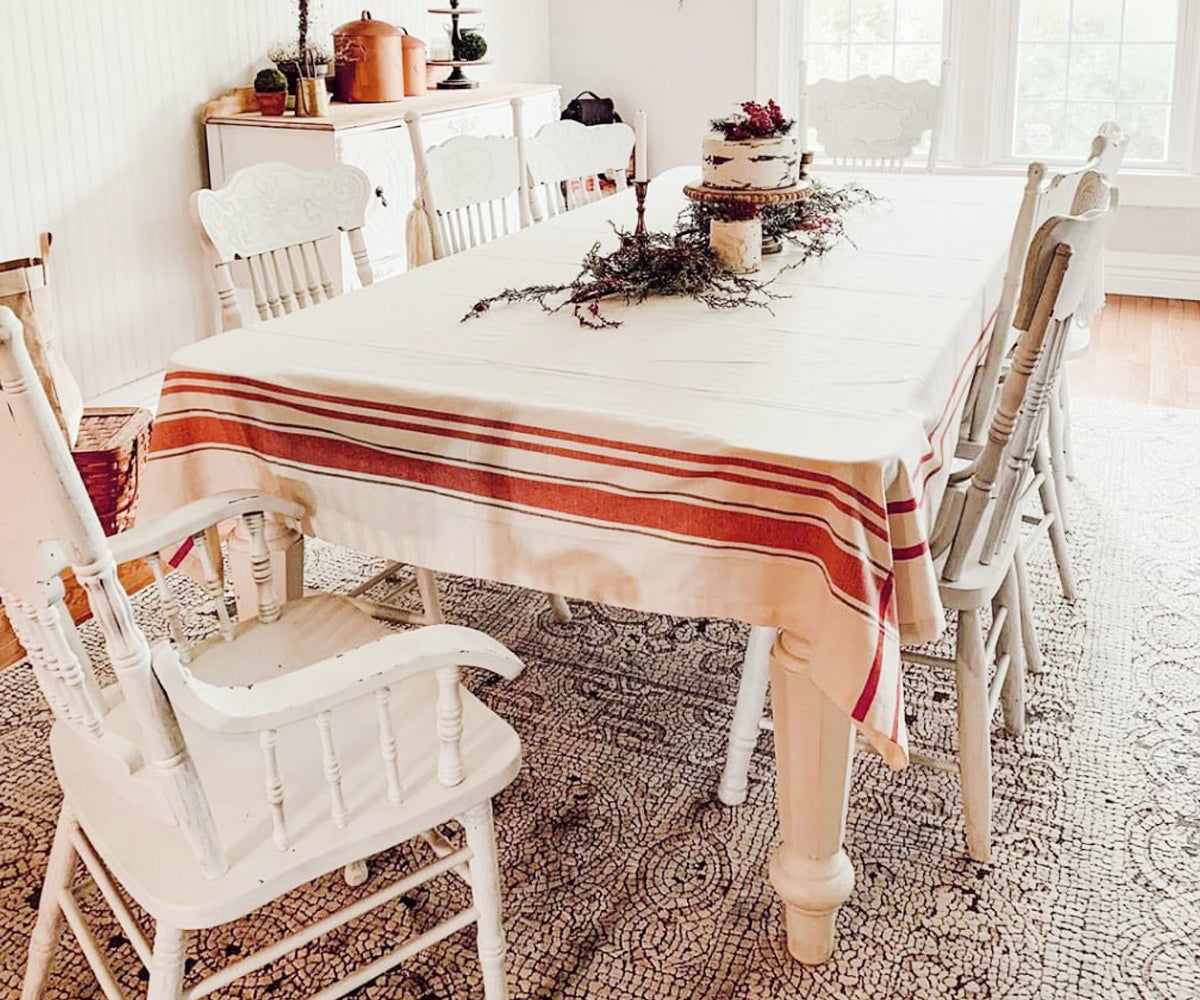 Dining room table with a French tablecloth in red and white stripes and white chairs