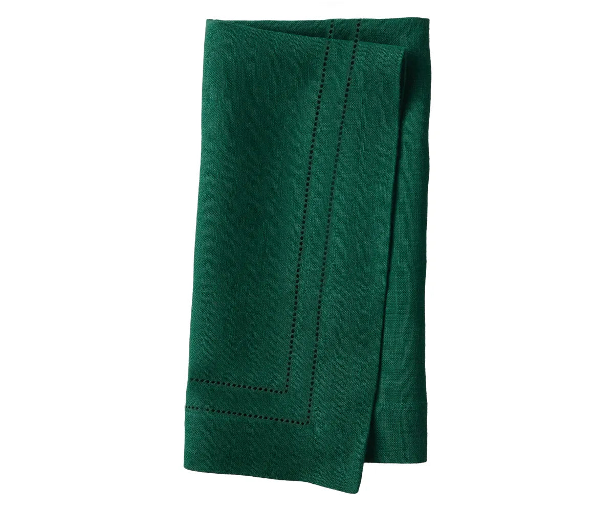 Green linen hemstitch napkins neatly folded on a dining table setup Green linen hemstitch napkins neatly folded on a dining table setup