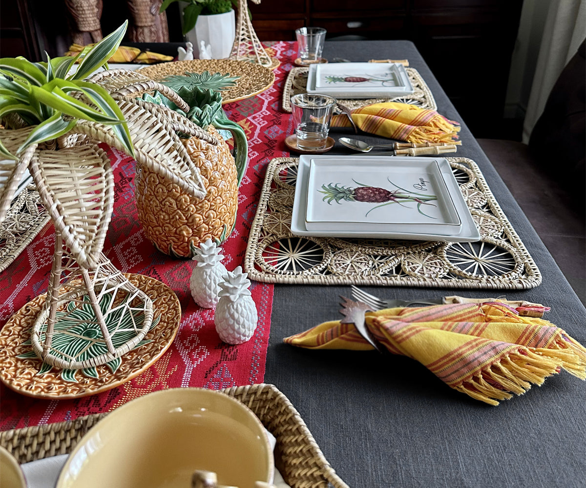 Hermstitched grey tablecloth with a tropical-themed table setting, featuring woven placemats, pineapple decor, and colorful napkins. Hermstitched grey tablecloth with a tropical-themed table setting, featuring woven placemats, pineapple decor, and colorful napkins.
