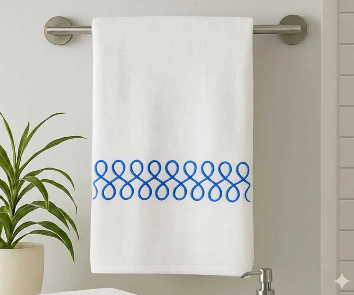White cotton bath towel with elegant royal blue embroidery displayed in a modern bathroom White cotton bath towel with elegant royal blue embroidery displayed in a modern bathroom