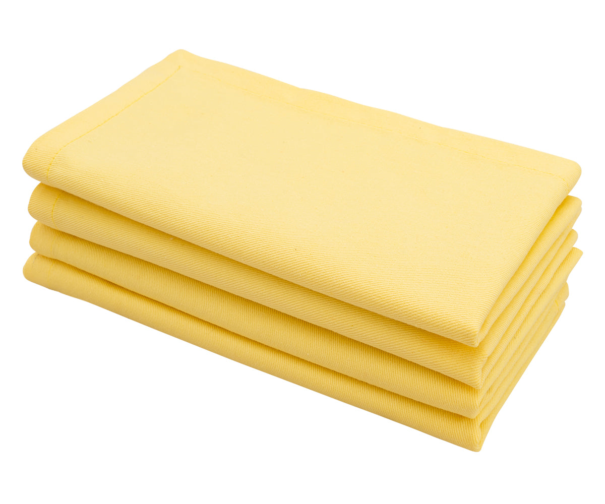 Lemon yellow cotton cloth dinner napkin neatly folded on a dining table. Lemon yellow cotton cloth dinner napkin neatly folded on a dining table.