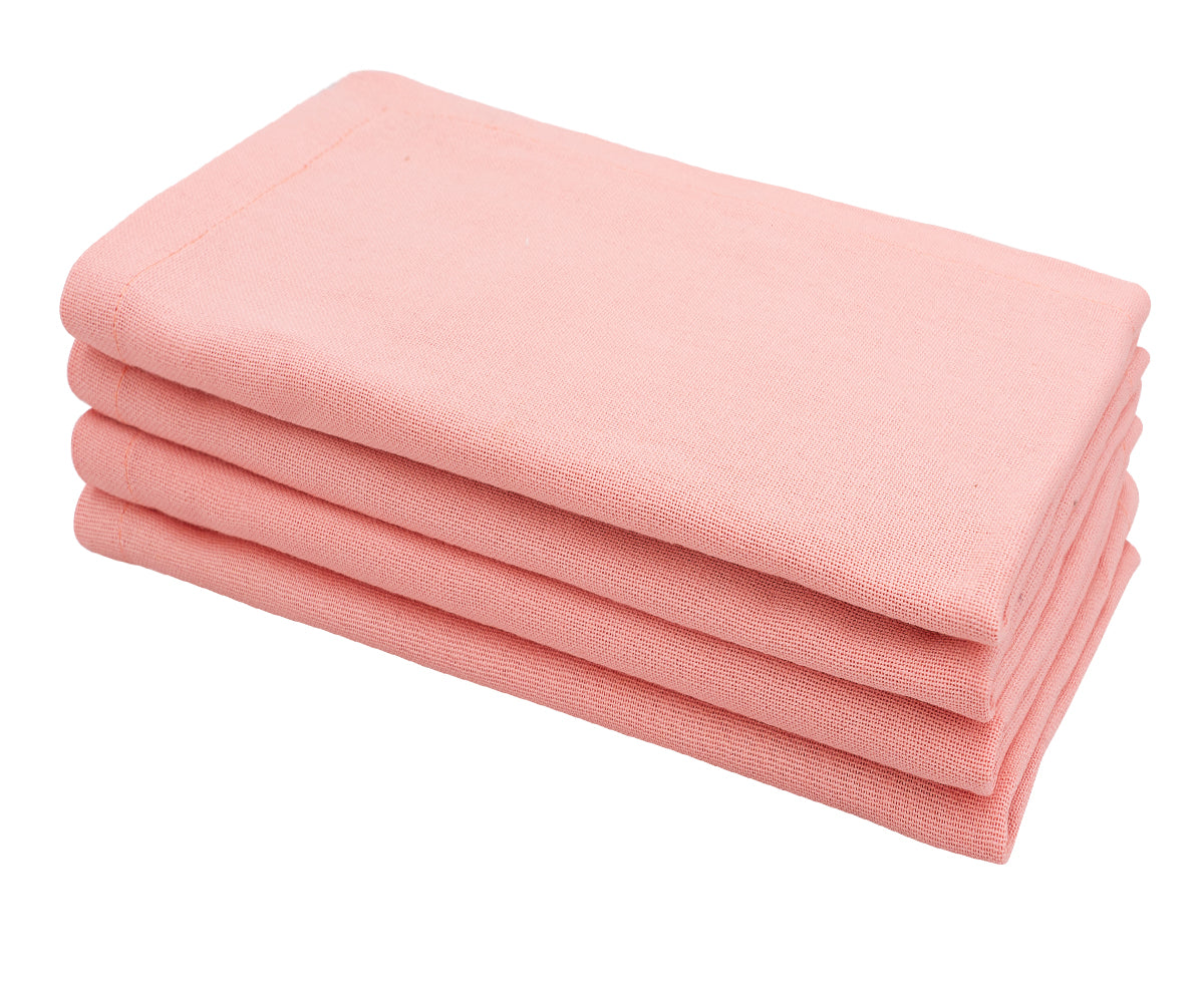 Light pink cotton cloth dinner napkin neatly folded on a dining table. Light pink cotton cloth dinner napkin neatly folded on a dining table.
