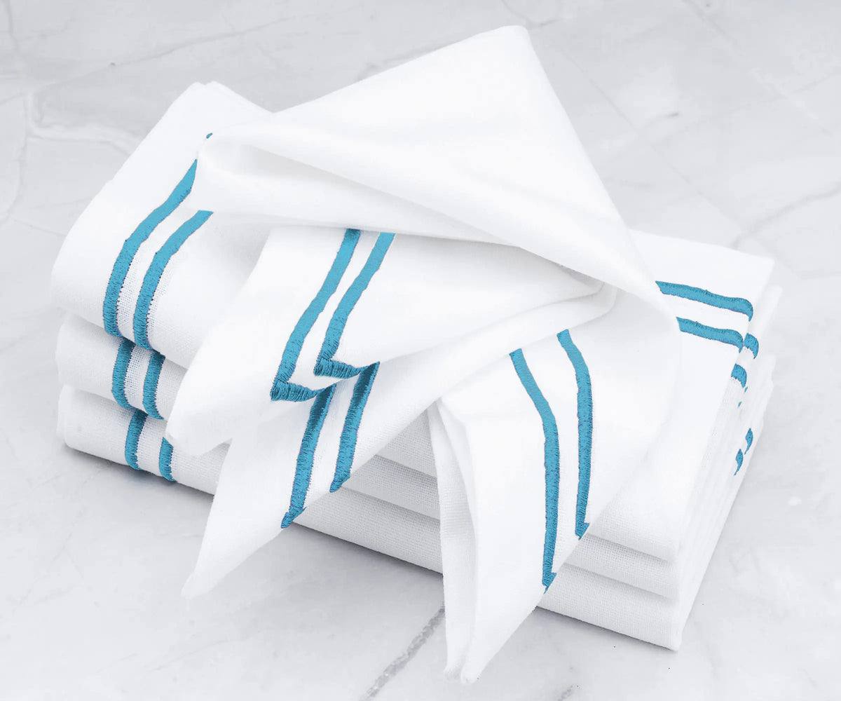 High-quality linen napkins featuring a double line of light blue embroidery. High-quality linen napkins featuring a double line of light blue embroidery.