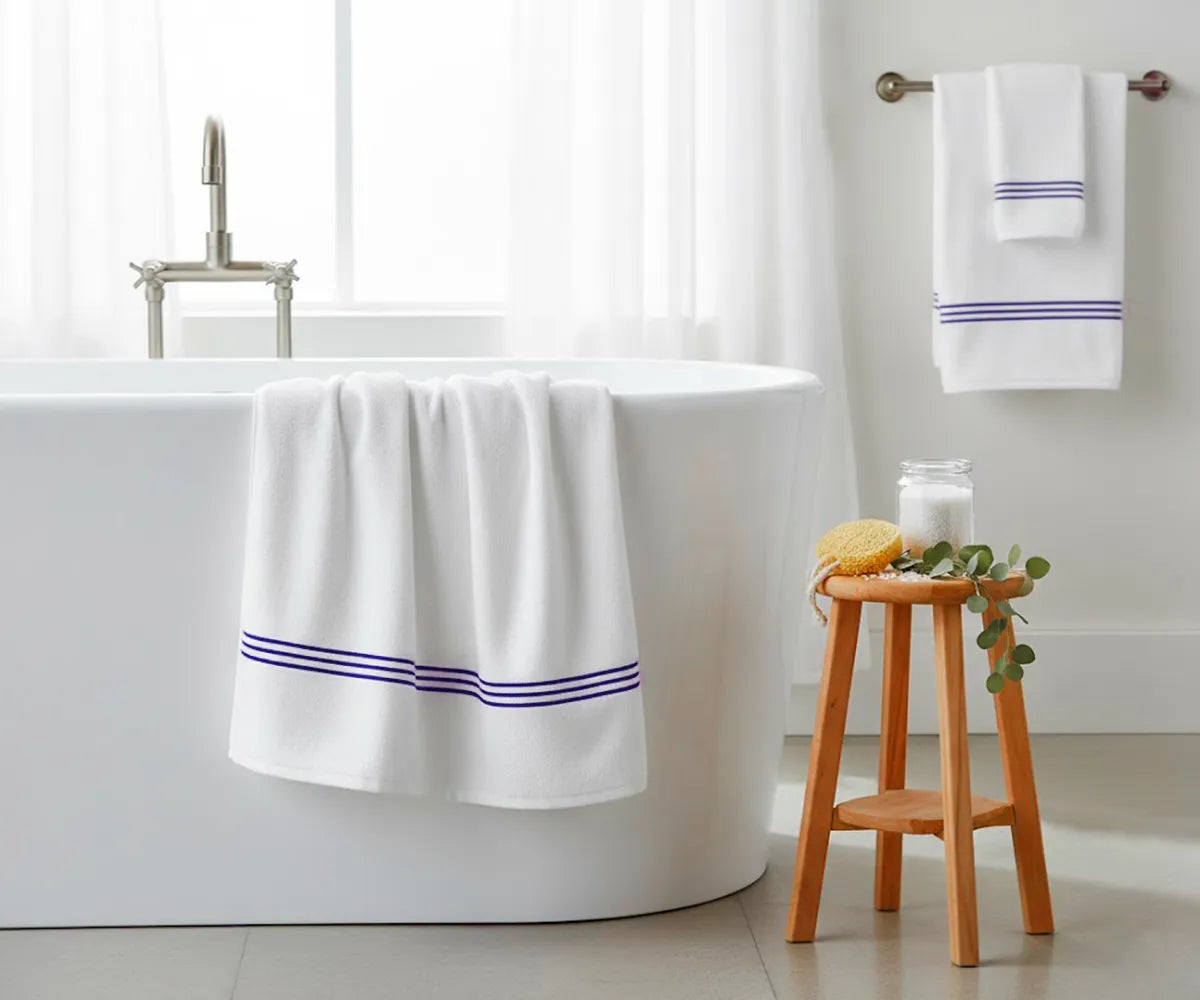 Soft white cotton bath towel with royal blue embroidered stripes, plush 820 GSM fabric, quick-drying, and durable — ideal for modern, elegant bathroom décor. Soft white cotton bath towel with royal blue embroidered stripes, plush 820 GSM fabric, quick-drying, and durable — ideal for modern, elegant bathroom décor.