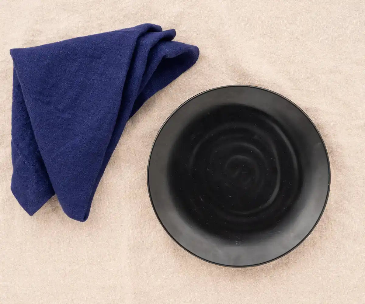 Blue linen plain dinner napkin elegantly folded on a dining table. Blue linen plain dinner napkin elegantly folded on a dining table.