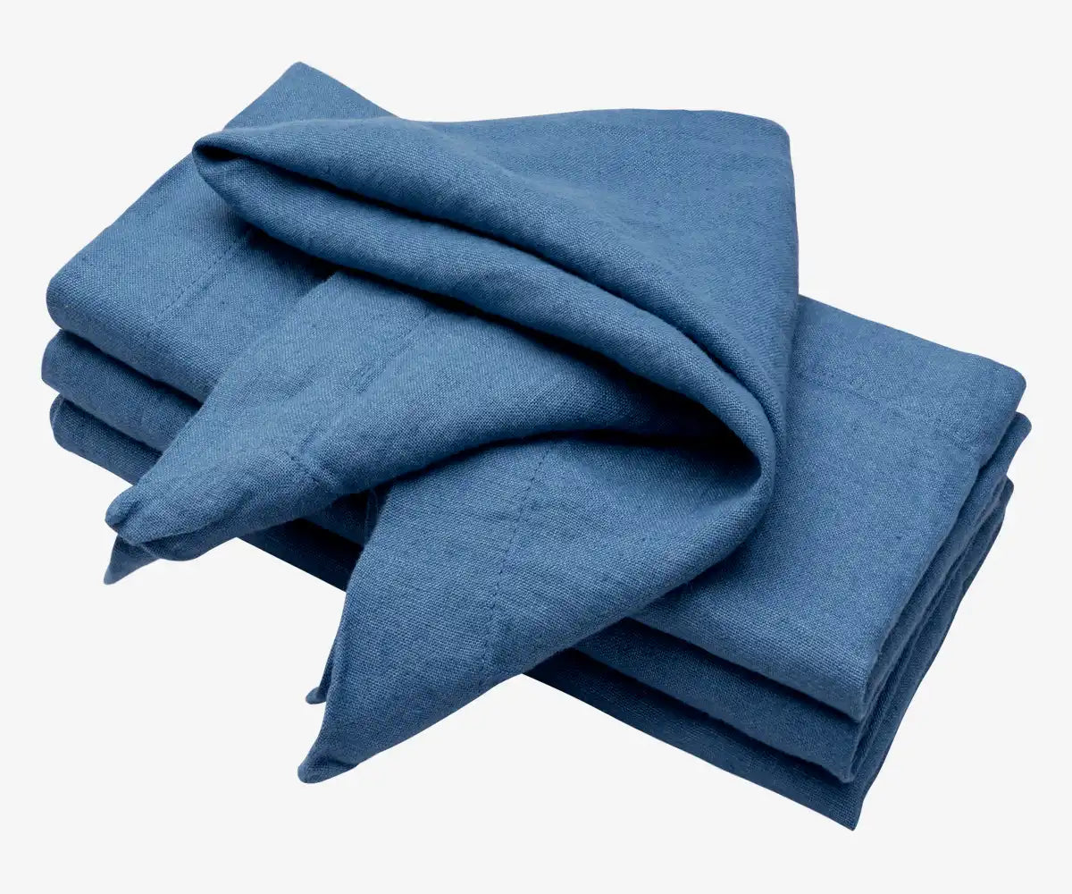 The photo features folded napkins in a shade of blue, possibly denim or a similar hue, made from a textured linen fabric. The photo features folded napkins in a shade of blue, possibly denim or a similar hue, made from a textured linen fabric.