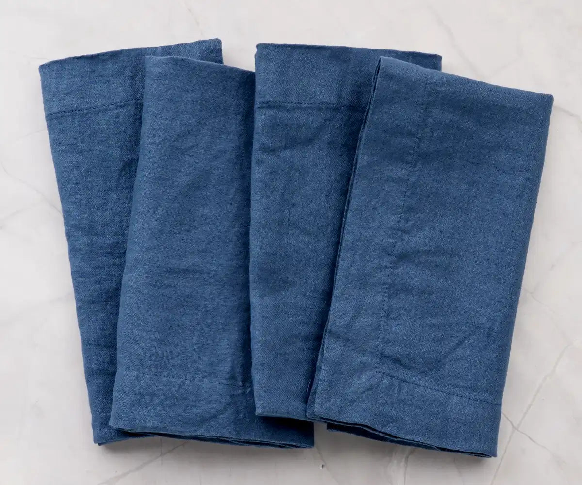 Four neatly folded blue cloth napkins on a light marble surface Four neatly folded blue cloth napkins on a light marble surface