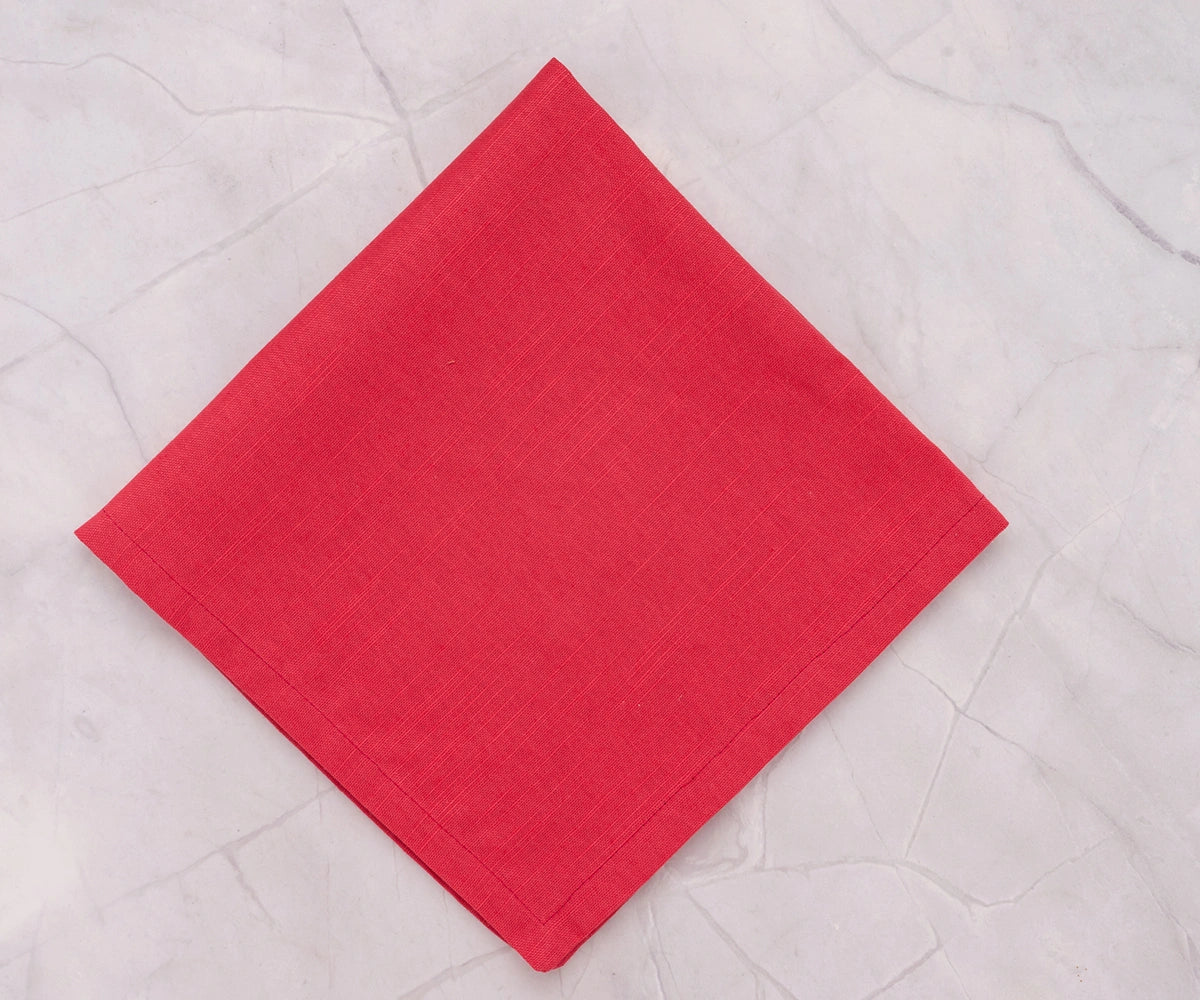 Maroon cotton dinner napkin folded neatly on a classic dining table setup. Maroon cotton dinner napkin folded neatly on a classic dining table setup.