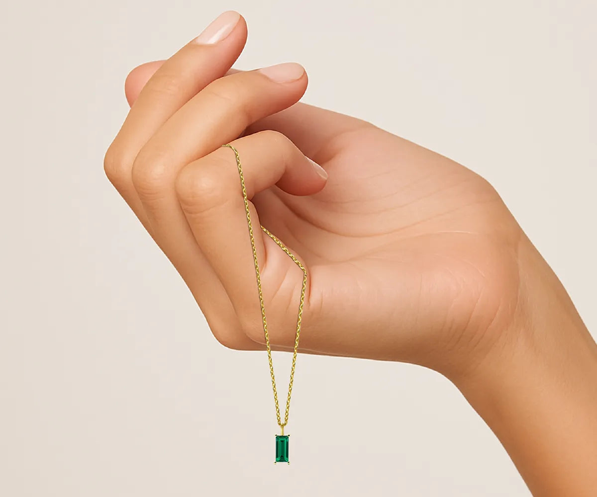 Emerald green baguette-cut necklace in gold – May birthstone pendant for women. Emerald green baguette-cut necklace in gold – May birthstone pendant for women.