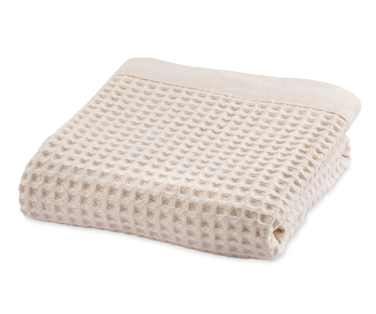 Natural cotton waffle blanket folded neatly on a bed with neutral bedding. Natural cotton waffle blanket folded neatly on a bed with neutral bedding.