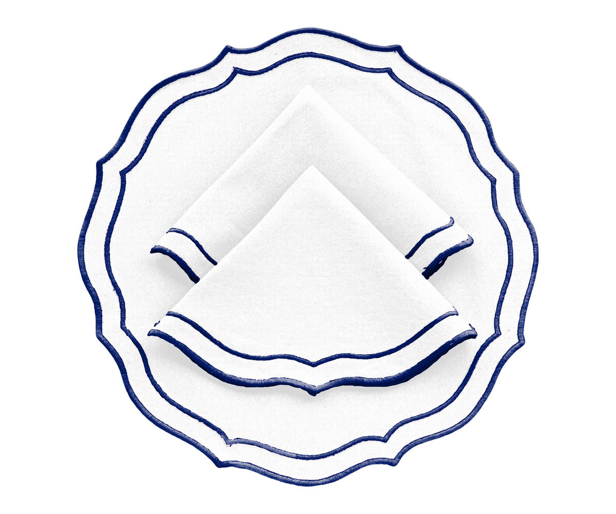Set of 4 navy blue round cotton placemats with scalloped edges on dining table Set of 4 navy blue round cotton placemats with scalloped edges on dining table