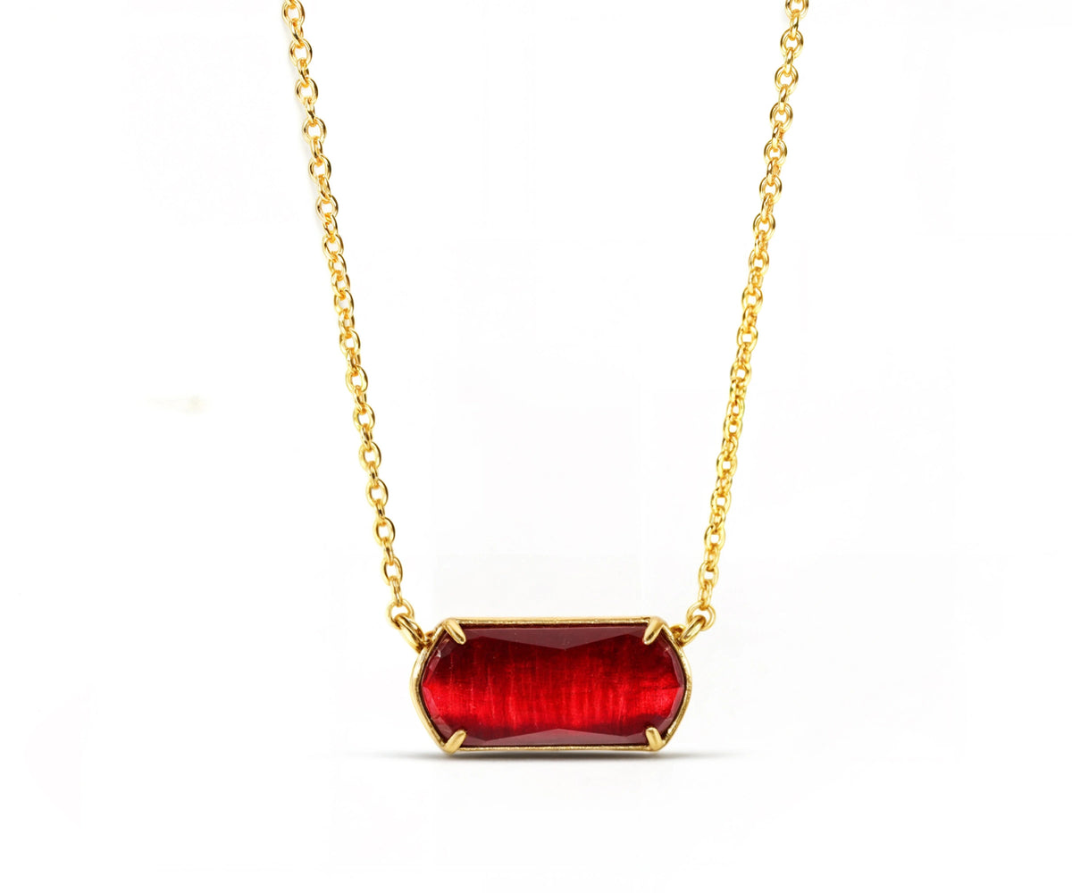 Close-up of a gold necklace with red pendant. Close-up of a gold necklace with red pendant.