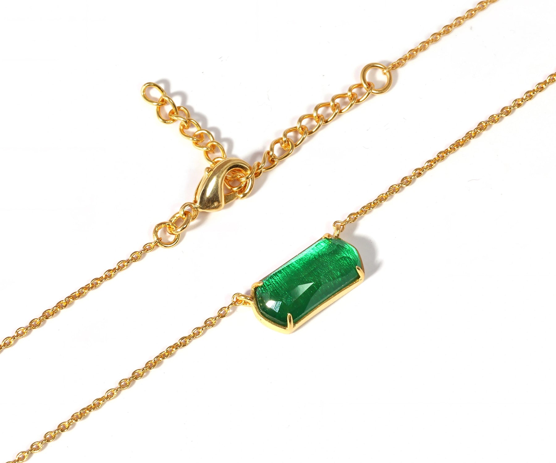 A chunky gold necklace with a green pendant. A chunky gold necklace with a green pendant.