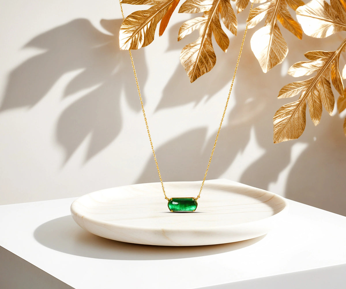 A chunky gold necklace with a emerald green pendant. A chunky gold necklace with a emerald green pendant.