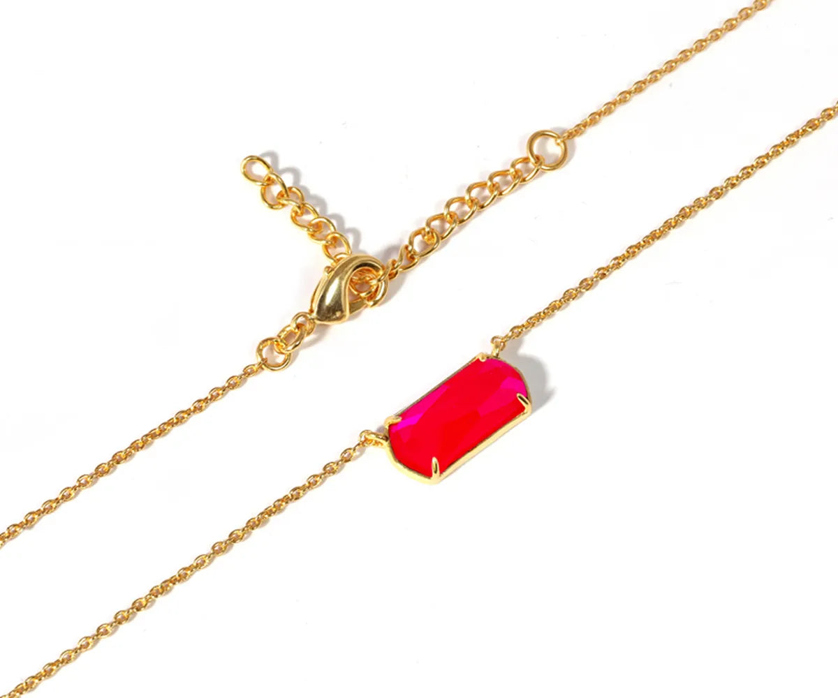 Close-up of custom-cut hot pink stone pendant on a delicate gold chain Close-up of custom-cut hot pink stone pendant on a delicate gold chain