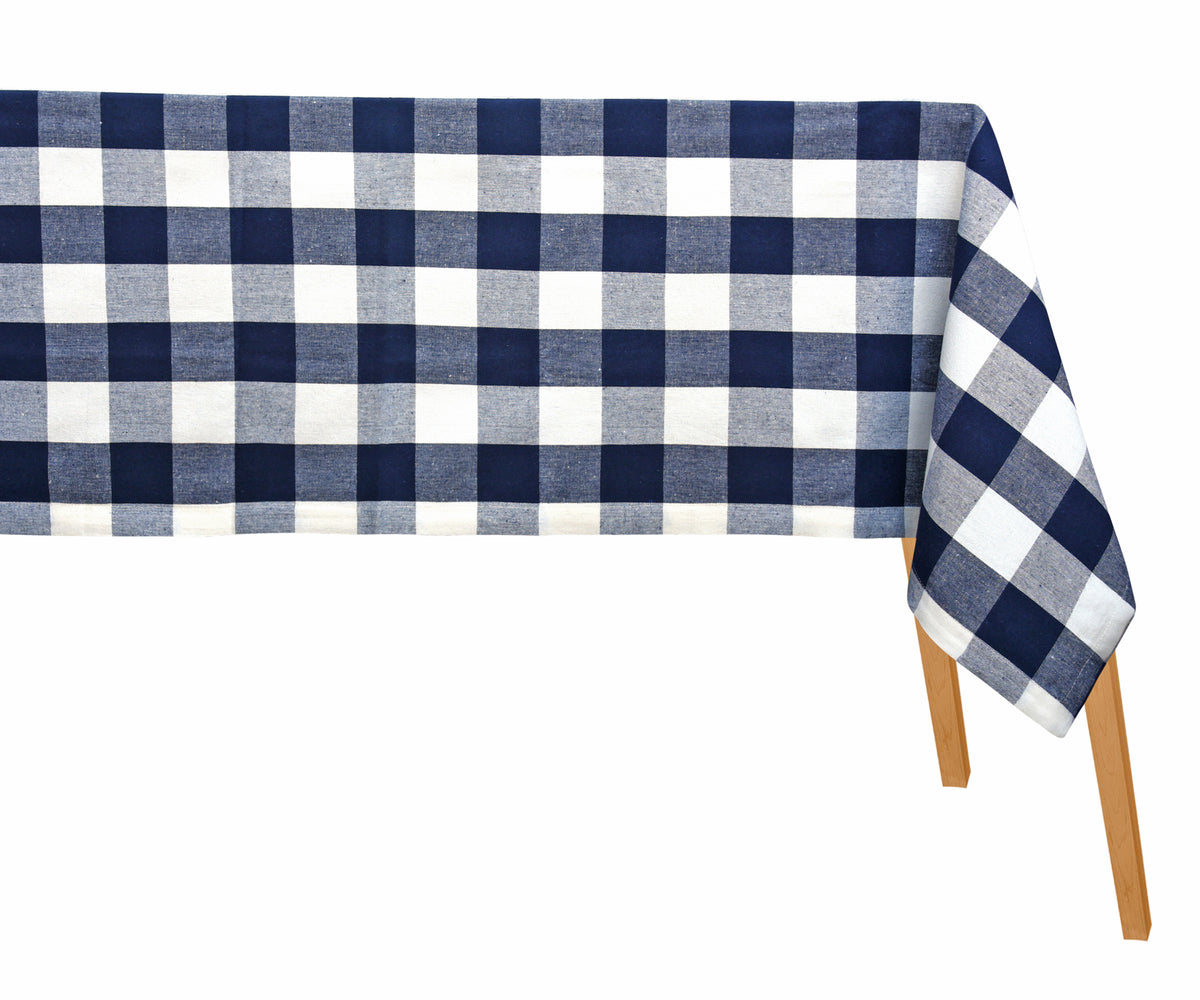 A rectangular checkered tablecloth in blue and white placed on a table with part of the table and legs visible. A rectangular checkered tablecloth in blue and white placed on a table with part of the table and legs visible.