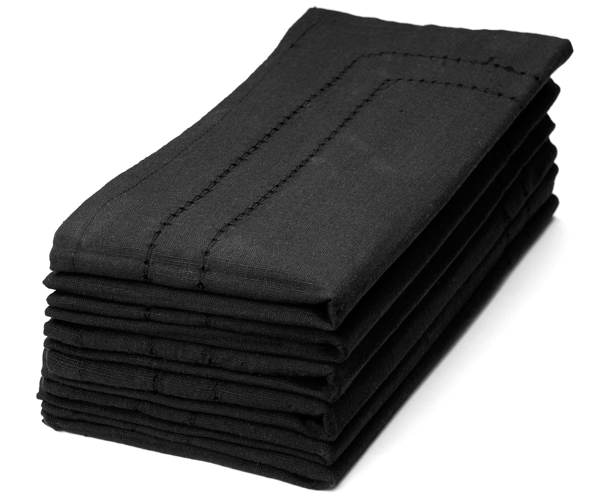 Elegant black napkins neatly folded and placed on a dining table, adding a touch of sophistication to the setting. Elegant black napkins neatly folded and placed on a dining table, adding a touch of sophistication to the setting.