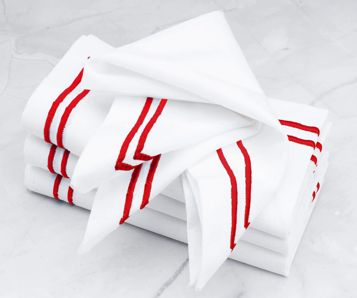 Luxury linen napkins featuring a double line of red embroidery. Luxury linen napkins featuring a double line of red embroidery.
