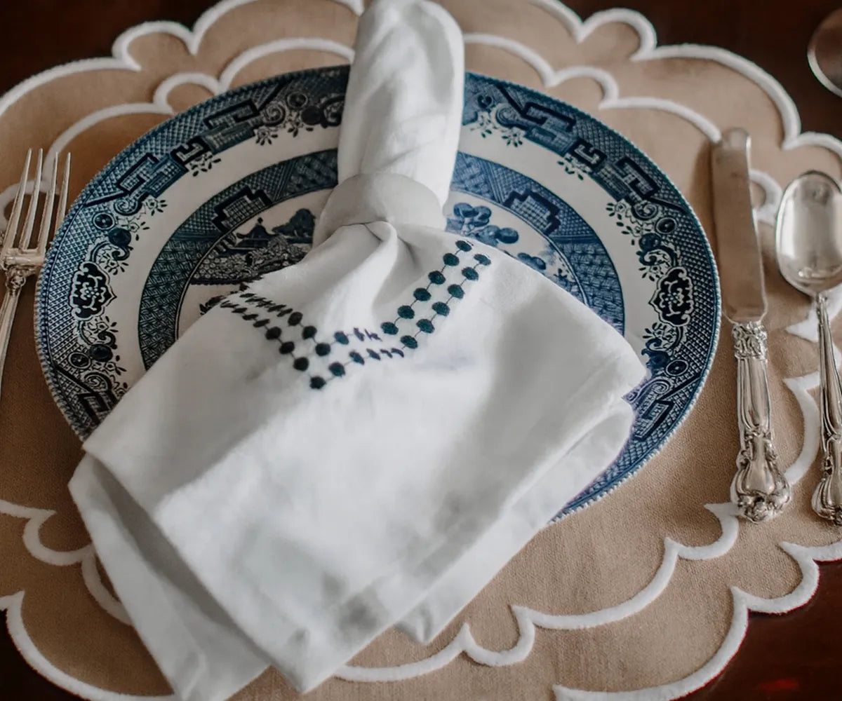 Decorative beige scalloped placemats with white trim, 17-inch and 15-inch sizes. Decorative beige scalloped placemats with white trim, 17-inch and 15-inch sizes.