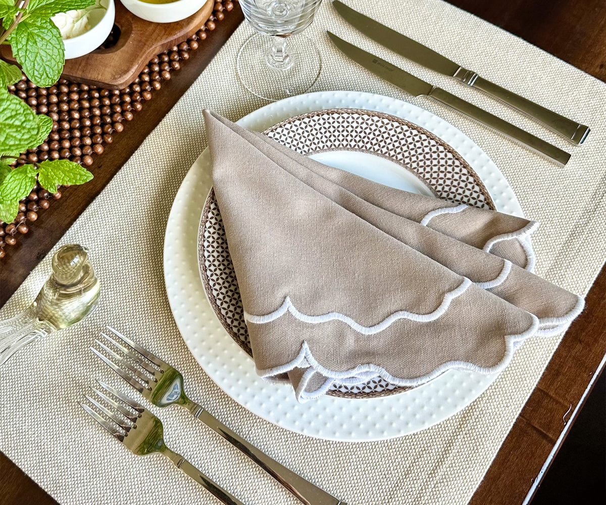 Close-up of finely stitched scallop edges on beige napkins. Close-up of finely stitched scallop edges on beige napkins.