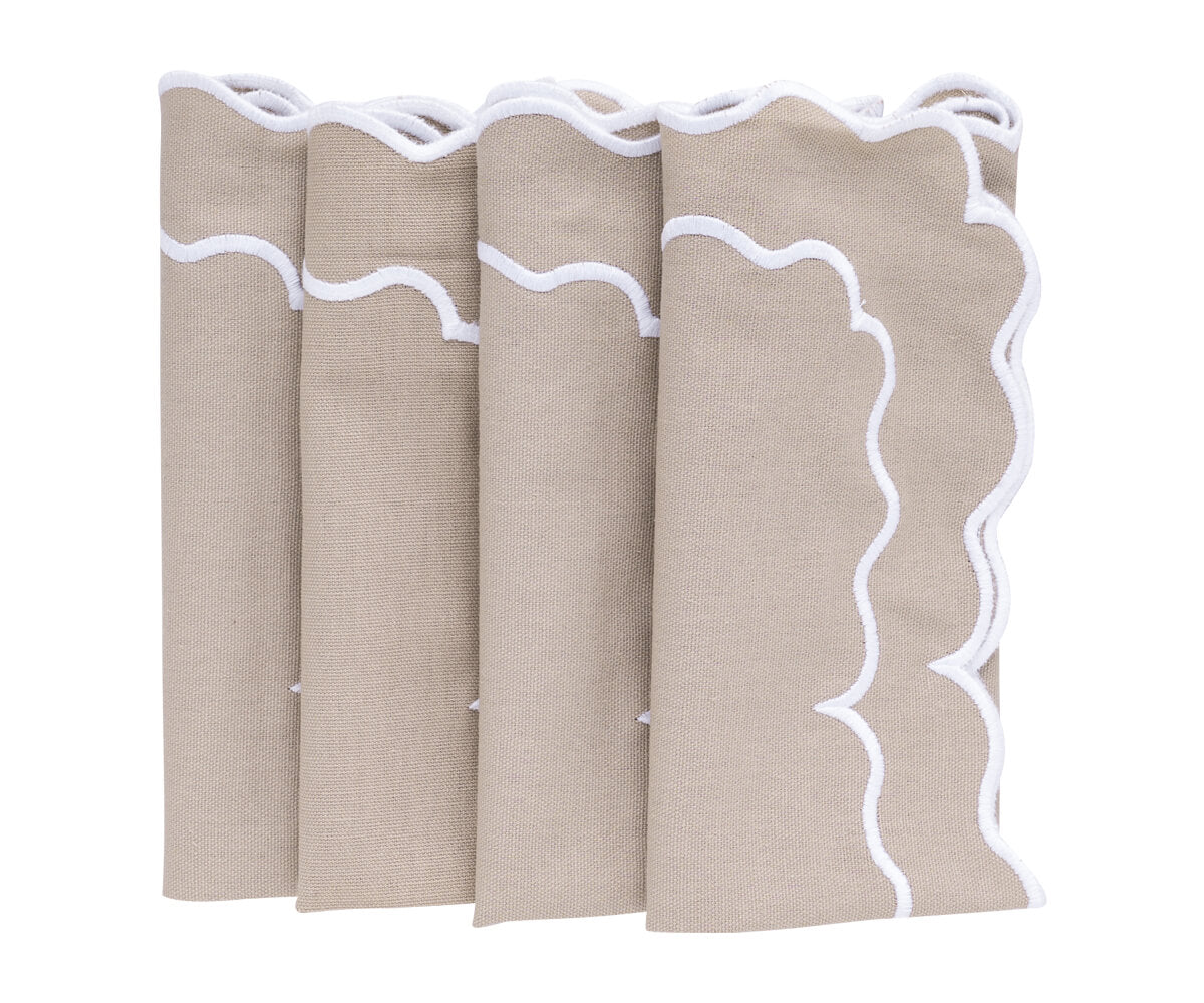 Close-up of beige scallop napkins with delicate embroidery on the edges. Close-up of beige scallop napkins with delicate embroidery on the edges.
