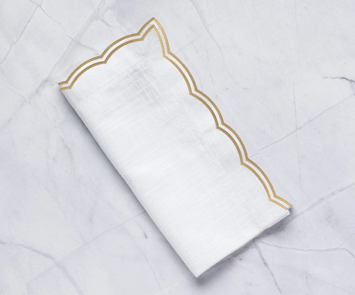 Beige scalloped cotton napkins with elegant double-scalloped embroidery on a dining table Beige scalloped cotton napkins with elegant double-scalloped embroidery on a dining table