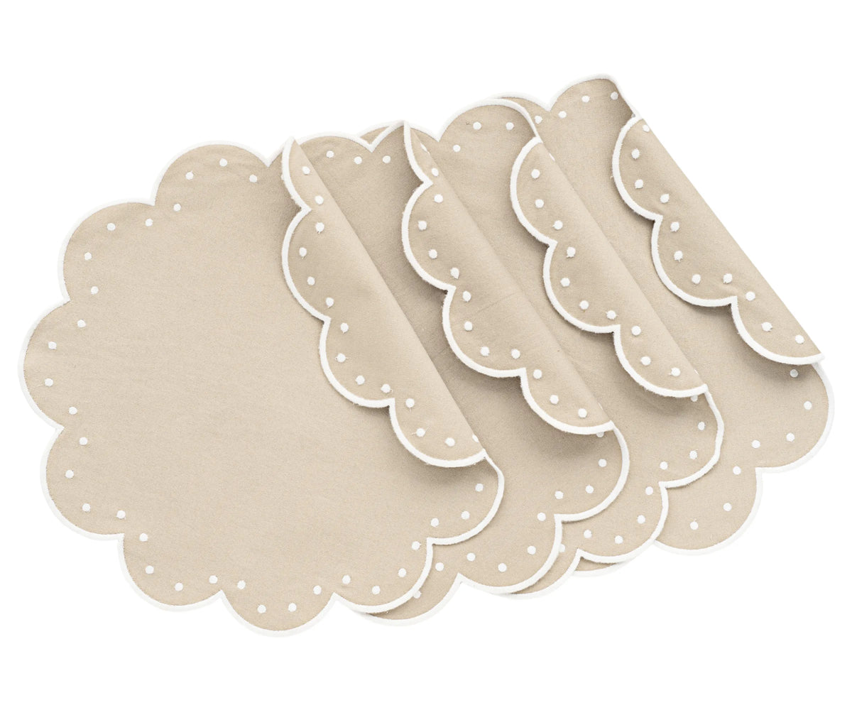 Light beige round scalloped cotton placemats on dining table Light beige round scalloped cotton placemats on dining table