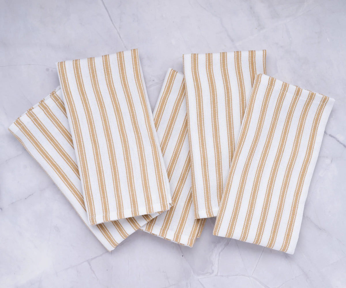 Beige cotton cloth napkins with white vertical stripes displayed on a dining table Beige cotton cloth napkins with white vertical stripes displayed on a dining table