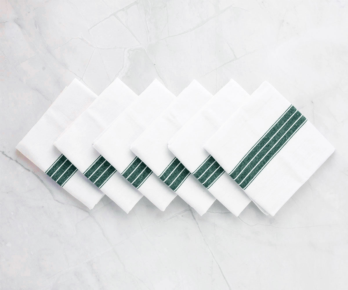 Green and white striped cotton napkin folded neatly on a dining table. Green and white striped cotton napkin folded neatly on a dining table.