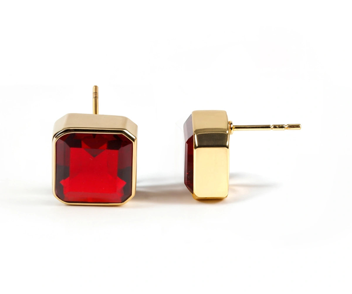 Close-up of garnet earrings studs with fiery red stones and gold setting. Close-up of garnet earrings studs with fiery red stones and gold setting.